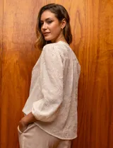 Blusa color crema de gasa bordada, con escote en V, abertura central con botones y mangas largas con puño.