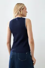 Chaleco tejido azul marino con cuello redondo y ribete blanco en cuello y sisas.