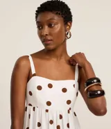 Vestido midi evasé sin mangas, confeccionado en tejido airflow color blanco con estampado de lunares marrones. Presenta escote corazón, breteles anchos con elásticos y lastex en la espalda.