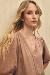 Vestido midi color marrón claro, con escote en V, mangas cortas abullonadas, botones frontales y falda con volantes.