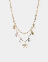 Collar corto dorado de doble cadena con dijes de cerámica, perlas, corazón y moño.