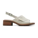 Sandalias bajas color blanco hueso, con tira ancha sobre el empeine y hebilla lateral. Taco bajo de madera.