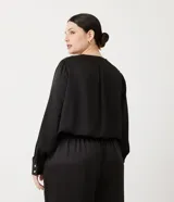 Blusa de satén negra con escote cruzado, manga larga y elástico en la cintura.