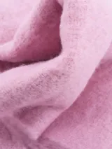 Bufanda rectangular tejida color rosa con flecos trenzados en los extremos.