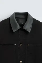 Parka negra de algodón con cuello solapa de cuero sintético, corte recto, acolchada, con bolsillos de parche y cierre frontal con botones.