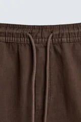 Bermuda de algodón color marrón oscuro, de corte regular fit, con cintura elástica ajustable mediante cordón. Presenta bolsillos laterales y un bolsillo trasero de vivo.