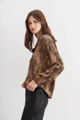 Camisa fluida con estampado reptil, escote redondo con apertura frontal y mangas largas terminadas en puño con botón.