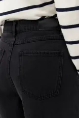 Pantalón de jean negro de calce ultra wide leg, tiro alto y silueta amplia desde la cadera hasta el bajo. Diseño clásico de cinco bolsillos y cierre con botón metálico y cremallera.