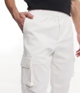 Pantalón cargo color beige con cintura elástica y ajuste en los tobillos. Cuenta con dos bolsillos laterales y dos bolsillos con cierre de solapa.