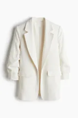 Blazer entallada color blanco, confeccionada en mezcla de viscosa. Modelo con hombreras, solapas de muesca, mangas tres cuartos fruncidas y bolsillos delanteros con solapa. Sin cierre y forrado.