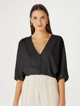 Blusa color beige con escote en V, mangas 3/4 abullonadas y cierre frontal con botones.