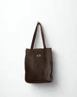 Bolso tipo tote de cuero color marrón oscuro con flecos frontales, cierre metálico y doble asa de hombro. Diseño boho chic.