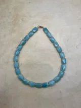 Collar corto de piedras facetadas rectangulares en rojo, blanco, negro y turquesa, con detalles dorados.