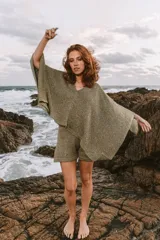 Poncho tejido color verde oliva con brillos dorados, de corte amplio y mangas murciélago. Incluye short haciendo juego.