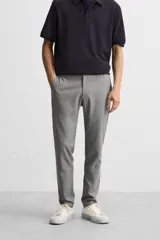 Pantalón negro de corte slim fit, confeccionado en tejido elástico. Cuenta con cintura elástica, bolsillos frontales y traseros de vivo. Cierre frontal con cremallera y botón.