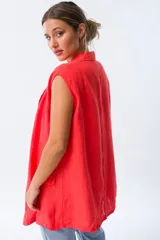 Chaleco largo color rojo coral, sin mangas, con solapas y bolsillos laterales. Confeccionado en lino.