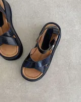 Sandalias negras de cuero vacuno con textura reptil, plataforma y hebilla plateada.