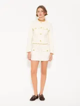 Conjunto de mini falda y chaqueta color crema con botones dorados y costuras en contraste.