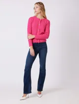Cardigan tejido color fucsia, con escote a la base y abertura central con botones metálicos dorados. Presenta bolsillos simulados en la parte delantera y terminación desflecada en la abertura y los bolsillos.