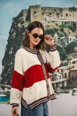 Cardigan tejido a rayas horizontales rojas y crema, con cuello redondo, cierre frontal con botones marrones y mangas largas abullonadas. Presenta ribetes a rayas en cuello, puños y ruedo. Tiene bordado el logo de la marca en el pecho.