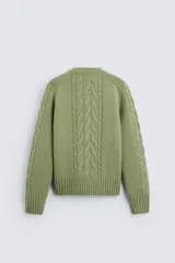 Sweater verde claro de punto con cuello redondo y mangas largas. Presenta diseño de trenzas en el centro y en las mangas.