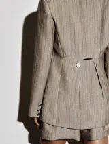 Blazer color beige con finas rayas verticales negras, de corte clásico, con solapas de muesca, cierre frontal con dos botones y bolsillos con solapa.