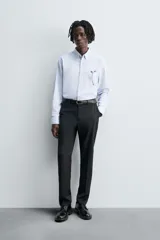 Camisa de algodón color celeste claro, corte regular fit, con cuello abotonado (button-down), manga larga con puño abotonado y bolsillo de parche en el pecho izquierdo.