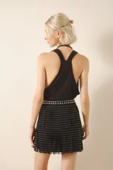 Minifalda negra de cuero gamuza con tachas bombé en la cintura y dos hileras de flecos con remaches metálicos plateados.
