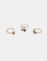 Set de tres anillos dorados con dijes de frutas con incrustaciones de strass: cerezas, frutilla y uvas.