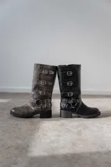 Bota de caña media color gris con múltiples hebillas metálicas.