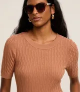 Blusa color ladrillo de punto con textura acanalada, cuello redondo y mangas cortas.