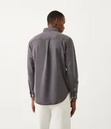 Camisa de hombre de manga larga, color gris oscuro, corte clásico, con cuello abotonado y cierre frontal con botones blancos.