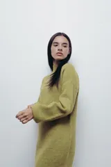 Vestido corto tejido de punto color fucsia, con cuello alto y mangas globo.