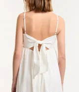 Vestido midi blanco con tirantes finos y escote cuadrado. Presenta bordados de caracolas en el busto y lazo en la espalda.