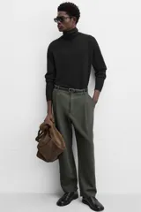 Pantalón relaxed fit color verde oscuro, con pliegues en la parte delantera, bolsillos laterales y traseros de ojal. Cierre frontal con cremallera y botón.