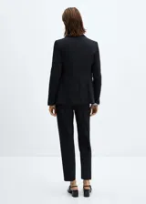 Blazer negro entallado con solapas de muesca, hombros estructurados, abertura posterior y dos bolsillos de ribete delanteros.