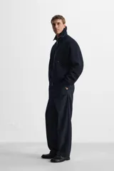 Pantalón de vestir azul marino, de corte recto, con bolsillos laterales y traseros. Incluye un bolsillo tipo cargo en la pierna izquierda. Se ajusta a la cintura con cinturón de cuero marrón.