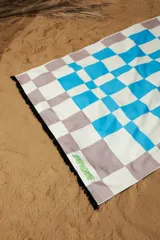 Pareo rectangular de algodón con diseño de damero en tonos celeste, blanco y marrón. Tiene flecos negros en los bordes y la inscripción "SYMPHORINE" en verde.