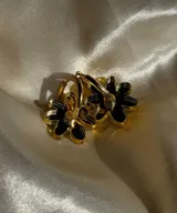 Par de aros dorados con dije de flor negra. El dije es de acrílico y el aro es dorado.