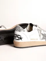 Zapatillas Golden Goose Ball Star de cuero blanco con estrella plateada brillante, refuerzo trasero plateado brillante, cordones grises y suela color caramelo.