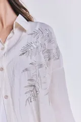 Camisa color crudo con bordados de lentejuelas plateadas en forma de hojas.