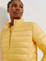 Campera puffer color crudo, confeccionada en poliéster con efecto matelassé, cuello alto y cierre frontal con cremallera.