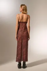 Vestido midi de poliéster con estampado animal print, breteles finos y volados en el escote. Corte al cuerpo y cuello redondo.