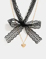 Collar corto con choker de encaje negro, cadena dorada y dije de corazón dorado.