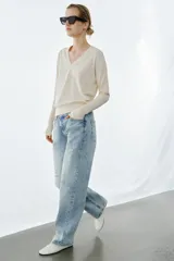 Jeans de tiro bajo, corte recto y largo completo, con efecto lavado y detalles de rotos en el delantero. Cierre frontal con cremallera y botón, y diseño de cinco bolsillos.