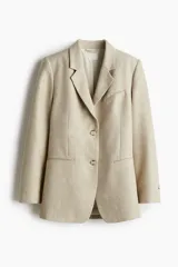 Blazer color beige de corte holgado con solapas de muesca, hombreras, abertura y botón en los puños, bolsillos delanteros ribeteados y bolsillo superior ribeteado. Forrado.