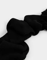 Bufanda larga de tejido de punto color negro con borde blanco y etiqueta de tela con logo en un extremo.