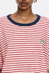 Camiseta de algodón color crema con rayas horizontales marrones, cuello redondo azul y logo bordado en el pecho.