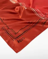 Pañuelo cuadrado de poliéster reciclado con estampado cartográfico en bloques de color naranja, rojo, bordó y gris. Presenta el logo de Adolfo Dominguez y detalles de texto inspirados en mapas.