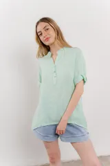 Blusa blanca de lino con escote en V abotonado y mangas cortas arremangadas.